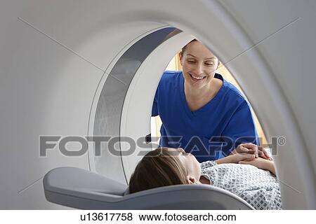 Stock Photo - Radiographer smiling at girl inside CT scanner. Fotosearch