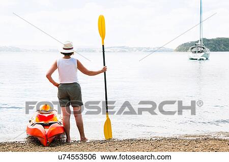 Stock Photograph - Rear view of senior woman and sea kayak. Fotosearch