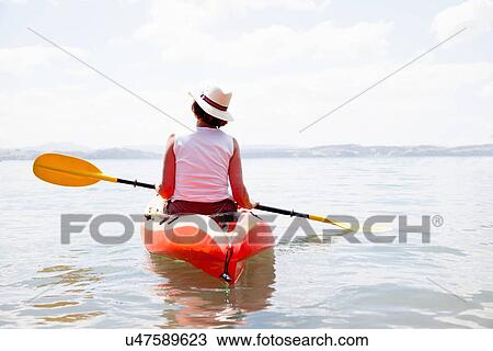 Stock Image - Rear view of senior woman sea kayaking. Fotosearch