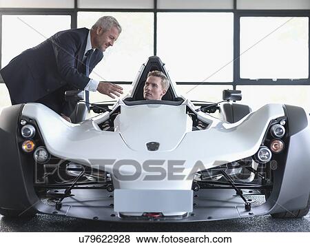 Salesman showing customer supercar in show room View Large Photo Image Stock Photo - Salesman showing customer supercar in show room. Fotosearch