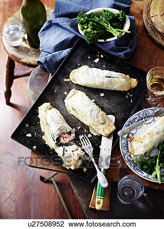 Stock Image - Salmon spinach filo pies, broccolini and wine. Fotosearch