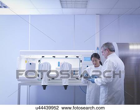 Scientists discussing notes in lab next to laboratory workstation View Large Photo Image Stock Image - Scientists discussing notes in lab next to laboratory workstation. Fotosearch