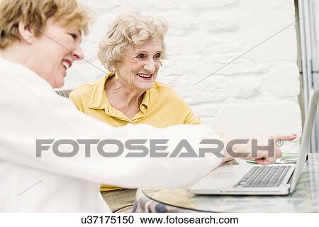 Senior woman and daughter looking at laptop View Large Photo Image Stock Image - Senior woman and daughter looking at laptop. Fotosearch