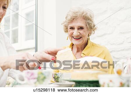 Stock Photo - Senior woman and daughter, slicing cake. Fotosearch