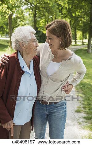 Senior woman and granddaughter standing in park View Large Photo Image Stock Photo - Senior woman and granddaughter standing in park. Fotosearch