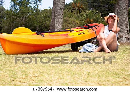 Stock Photo - Senior woman sitting cross legged on beach. Fotosearch