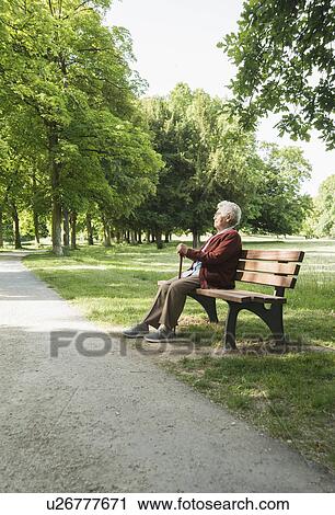 Senior woman sitting on park bench in park View Large Photo Image Stock Image - Senior woman sitting on park bench in park. Fotosearch