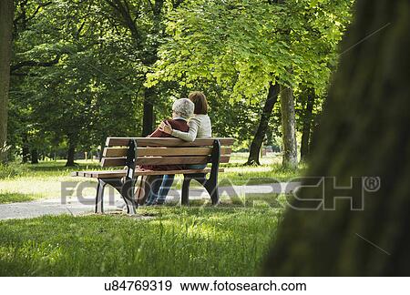 Senior woman sitting on park bench with granddaughter View Large Photo Image Stock Photo - Senior woman sitting on park bench with granddaughter. Fotosearch