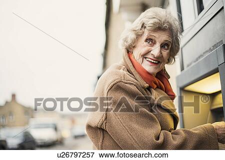 Stock Photo - Senior woman using cash machine. Fotosearch