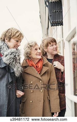 Stock Image - Senior woman with daughter and granddaughter, looking in window. Fotosearch