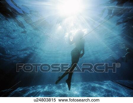 stock image of silhouette of girl swimming underwater u24803815