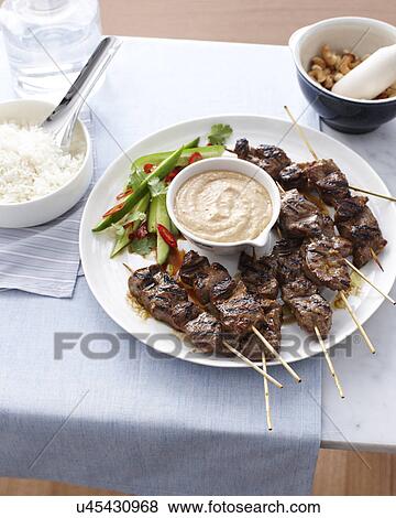 Stock Photo - Still life of beef skewers and satay sauce. Fotosearch