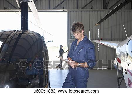 Stock Image - Student pilot checking details on clipboard. Fotosearch