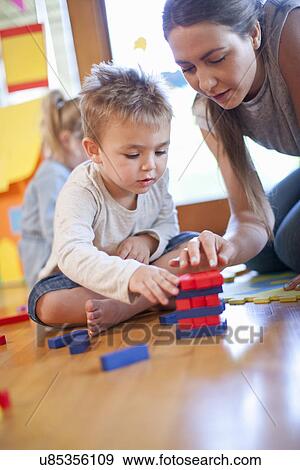 Stock Photo - Teacher and boy constructing building blocks at nursery school. Fotosearch