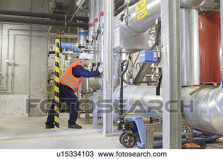 Stock Image - Technician leaning forward during check in power station. Fotosearch