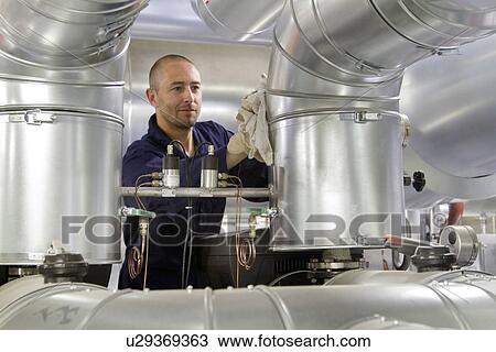 Stock Image - Technician monitoring pipes in power station. Fotosearch