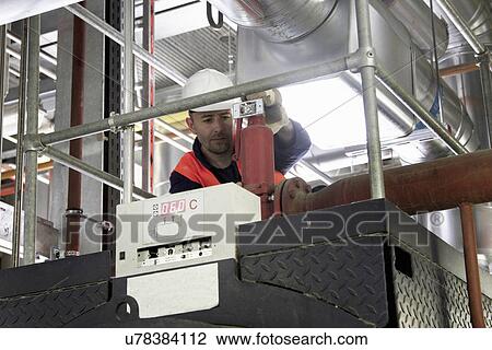 Stock Image - Technician on walkway doing check in power station. Fotosearch