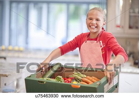 Teenage girl carrying vegetable box in kitchen View Large Photo Image Stock Image - Teenage girl carrying vegetable box in kitchen. Fotosearch