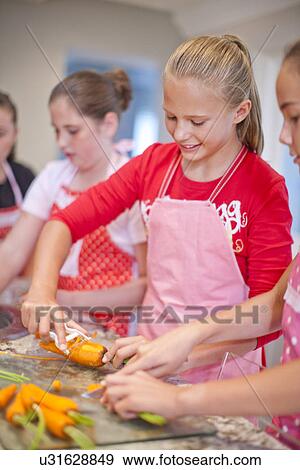 Stock Photo - Teenage girls preparing carrots in kitchen. Fotosearch