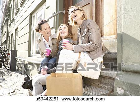 Stock Image - Three generation females drinking takeaway coffee on street. Fotosearch