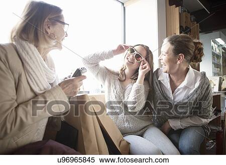 Stock Photography - Three generation females trying on sunglasses in shop. Fotosearch