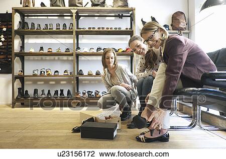 Stock Image - Three generation females trying out shoes in shoe shop. Fotosearch