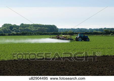 Stock Photography - Tractor and crop sprayer spraying in field. Fotosearch