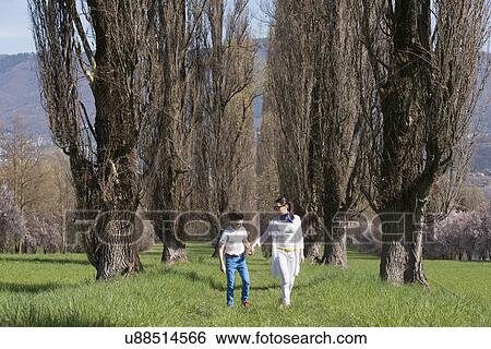 Twelve year old boy and mature mother strolling along tree lined field View Large Photo Image Stock Photograph - Twelve year old boy and mature mother strolling along tree lined field. Fotosearch