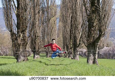 Twelve year old boy jumping mid air in tree lined field View Large Photo Image Stock Photo - Twelve year old boy jumping mid air in tree lined field. Fotosearch