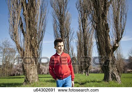 Twelve year old boy strolling along tree lined field View Large Photo Image Stock Image - Twelve year old boy strolling along tree lined field. Fotosearch
