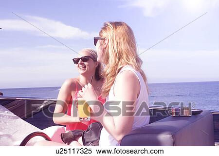 Stock Photography - Two adult female friends laughing on board yacht. Fotosearch