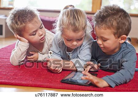 Two boys and a girl using digital tablet at nursery school View Large Photo Image Stock Photo - Two boys and a girl using digital tablet at nursery school. Fotosearch