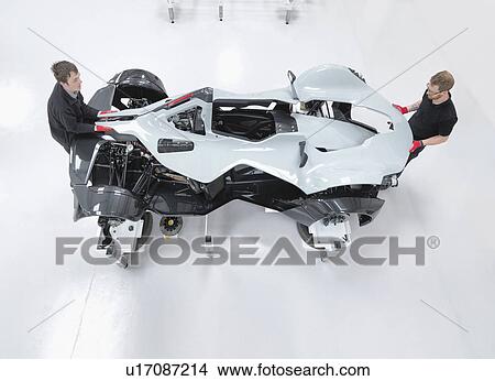 Two engineers assembling supercar in sports car factory, overhead view View Large Photo Image Picture - Two engineers assembling supercar in sports car factory, overhead view. Fotosearch