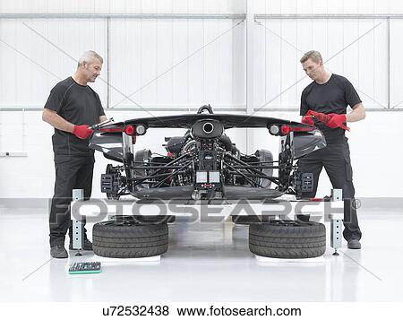 Stock Photo - Two engineers assembling supercar in sports car factory. Fotosearch