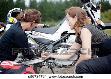 Two female motorcyclists checking motorcycle View Large Photo Image Picture - Two female motorcyclists checking motorcycle. Fotosearch
