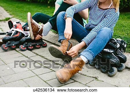Two sisters sitting on sidewalk unzipping boots for rollerblades View Large Photo Image Picture - Two sisters sitting on sidewalk unzipping boots for rollerblades. Fotosearch
