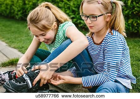 Two sisters sitting on sidewalk fastening rollerblades View Large Photo Image Stock Photograph - Two sisters sitting on sidewalk fastening rollerblades. Fotosearch