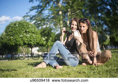 Stock Photo - Two young female friends in park taking self portrait on smartphone. Fotosearch