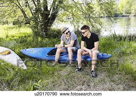 Two young men sitting on a canoe View Large Photo Image Stock Image - Two young men sitting on a canoe. Fotosearch