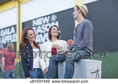 Two young women and mid adult man flirting on city street View Large Photo Image Stock Photo - Two young women and mid adult man flirting on city street. Fotosearch