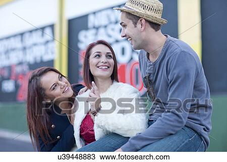 Two young women flirting with mid adult man on city street View Large Photo Image Stock Image - Two young women flirting with mid adult man on city street. Fotosearch