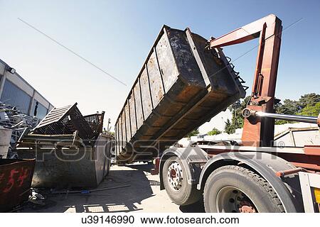 Stock Image - Unloading skip in scrap metal yard. Fotosearch