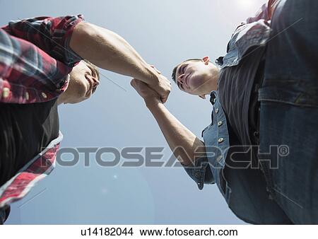 View from below of young men, shaking hands View Large Photo Image Picture - View from below of young men, shaking hands. Fotosearch