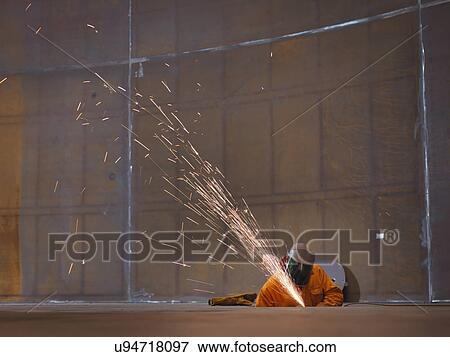 Stock Photo - Worker grinding in marine fabrication factory. Fotosearch