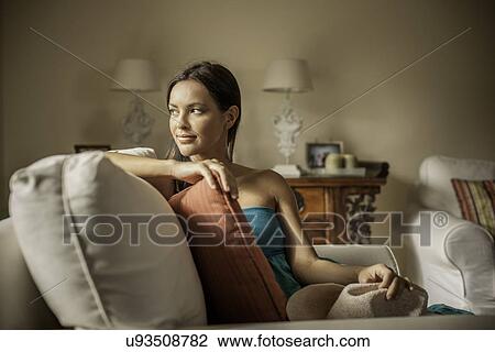 Stock Image - Young contemplative woman sitting in armchair. Fotosearch