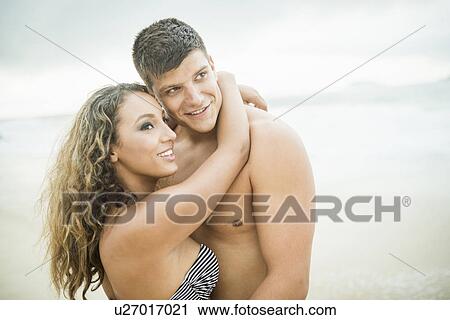 Stock Image - Young couple hugging, Ipanema Beach, Rio de Janeiro, Brazil. Fotosearch