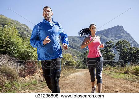 Stock Photo - Young couple jogging in forest. Fotosearch