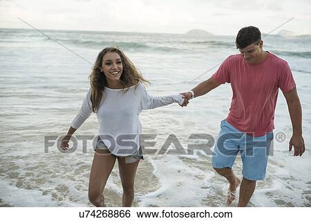 Stock Photograph - Young couple paddling in sea, Ipanema Beach, Rio de Janeiro, Brazil. Fotosearch