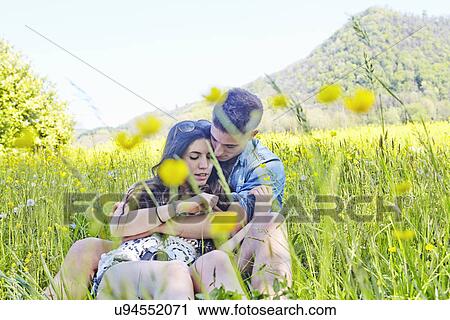 Stock Image - Young couple sitting in field. Fotosearch