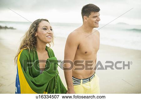 Stock Photo - Young couple strolling on beach, woman wrapped in brazilian flag, Ipanema Beach, Rio de Janeiro, Brazil. Fotosearch